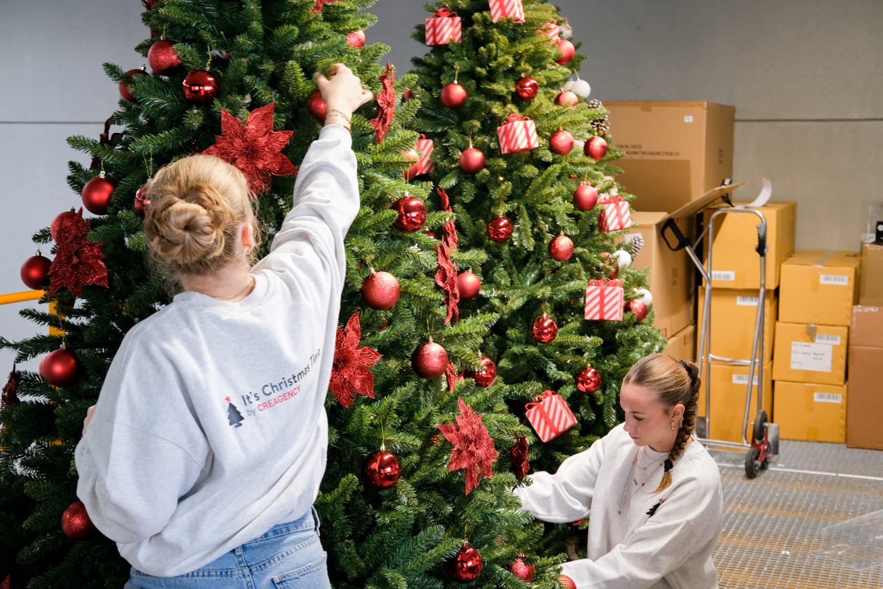 Nos décoratrices finalisent plusieurs sapins rouges dans notre atelier