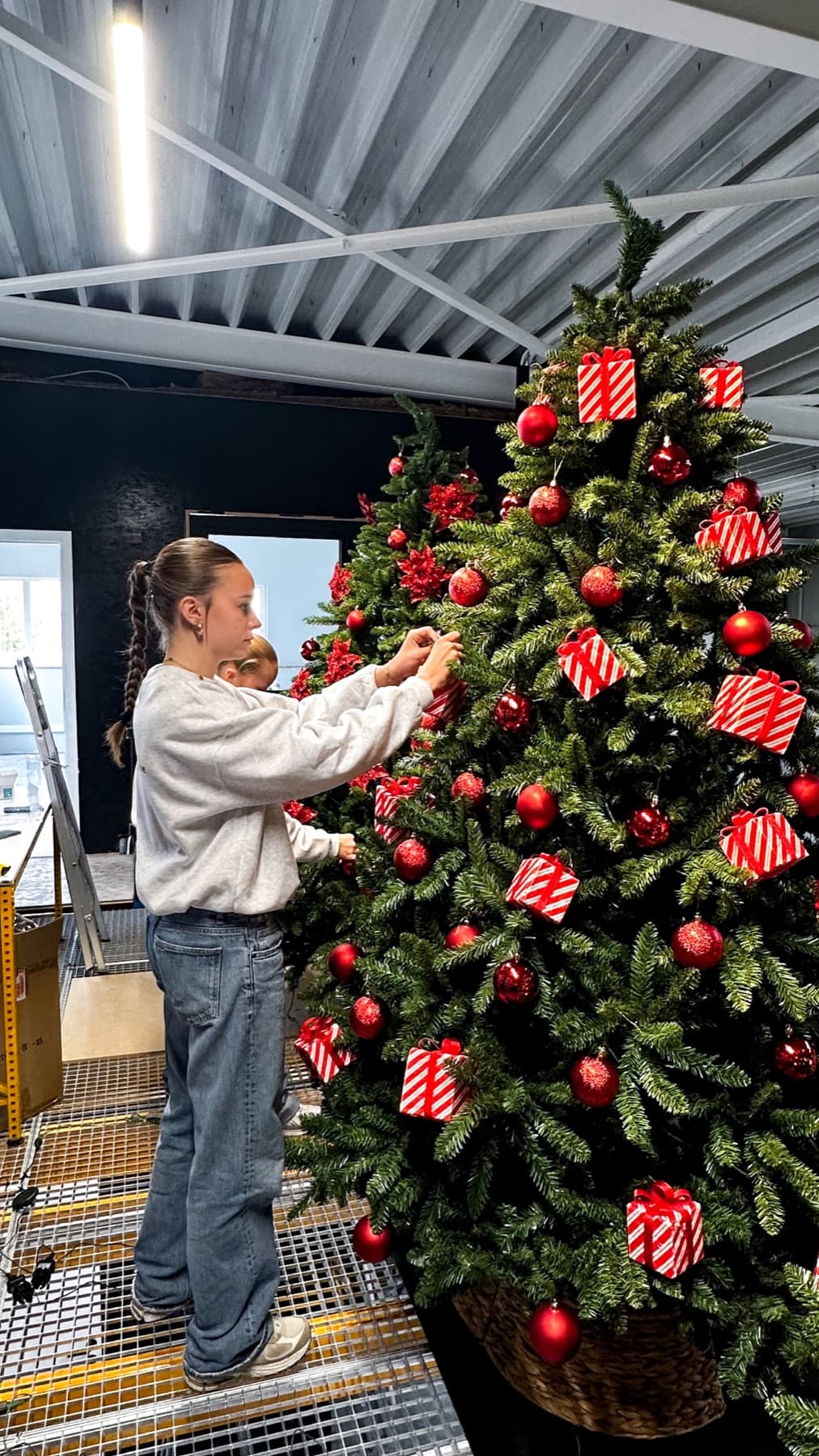 Une décoratrice apporte les dernières finitions à un grand sapin